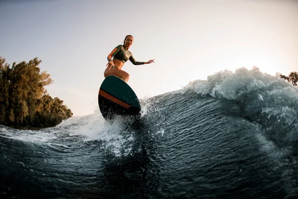 Atlético húmedo mujer haciendo truco con wakesurf en salpicadura ola. —  Fotos de Stock