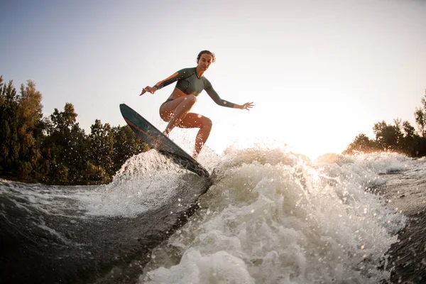 Femme en forme active faisant tour et sauter avec wakesurf sur la vague éclaboussante. — Photo