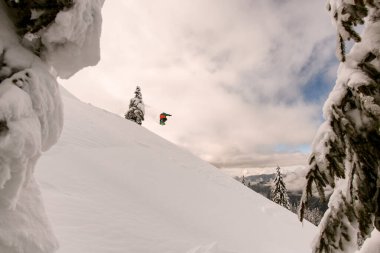 Dağ yamacının güzel manzarası ve atlayan snowboardcu.