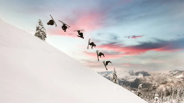Fantastisk utsikt över snöig bergssluttning och skidåkare gör trick i att hoppa genom luften — Stockfoto