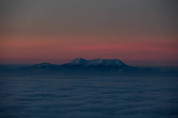 Luchtfoto van de avondlucht met wolken en bergtoppen bedekt met witte sneeuw. — Stockfoto