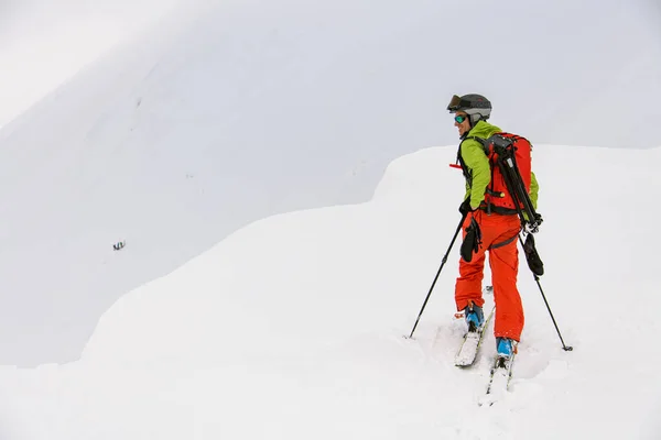 Visão traseira do esquiador homem com postes de trekking andando ao longo da encosta da montanha nevada — Fotografia de Stock