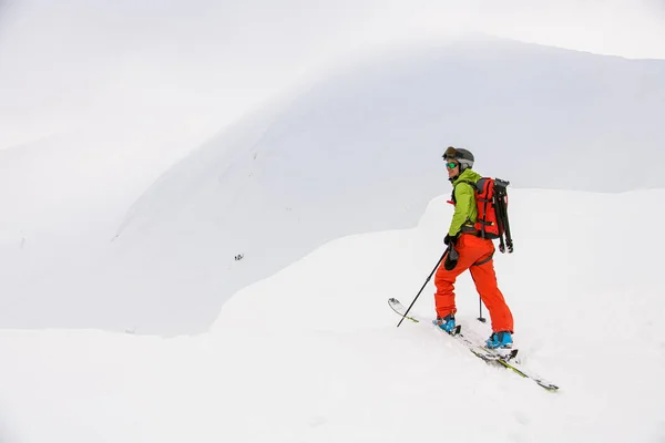 Вид лыжника с треккинговыми палками, идущего по снежному склону горы — стоковое фото
