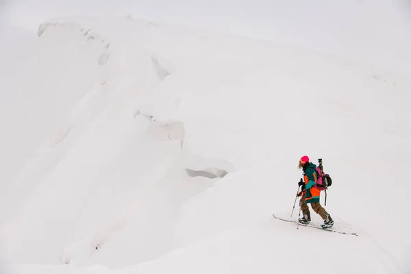 Высокий угол обзора лыжника с треккинговыми палками, идущего вдоль снежного склона горы — стоковое фото