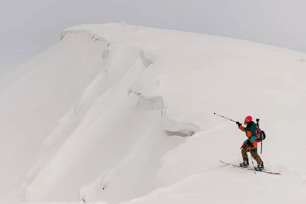 Nagyszerű kilátás az ember síelő mutató irányba túraoszlopok havas hegyi lejtőn — Stock Fotó