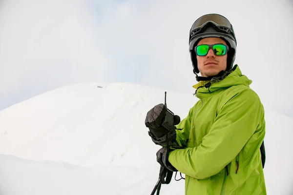 戴着太阳镜和滑雪头盔的男人手里拿着对讲机，在白雪的衬托下 — 图库照片