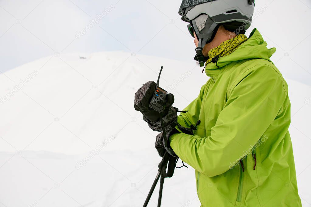 man skier holds his hands a walkie-talkie on a background of white snow