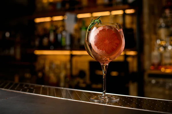Hermosa copa de vidrio con bebida fría decorado por una rebanada de pomelo y rama de romero fresco — Foto de Stock