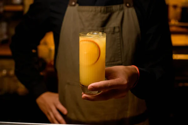 男性の手にオレンジの果実のスライスと冷たいアルコールカクテルとガラス — ストック写真