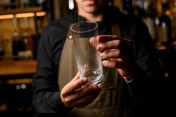 Χέρια ενός άνδρα μπάρμαν απαλά κρατήστε άδειο διαφανές ψηλό ποτήρι κοκτέιλ. — Φωτογραφία Αρχείου