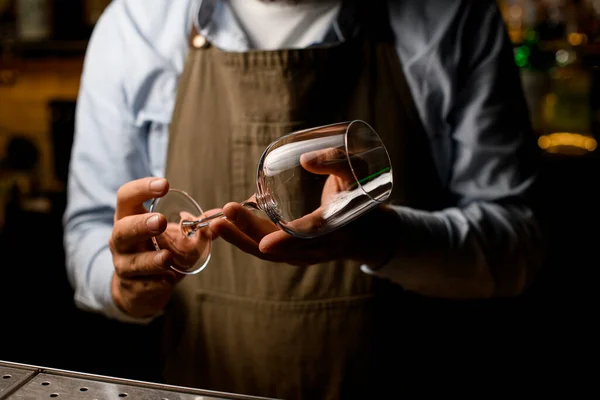 Чоловічі руки бармена акуратно тримають порожній келих для вина . — стокове фото
