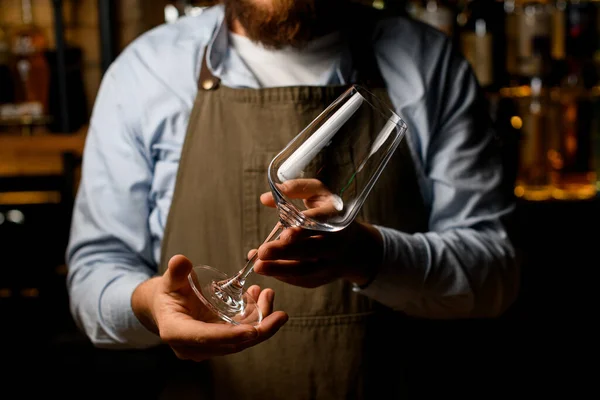 Nahaufnahme kaukasischer Barkeeper Hände, die ein leeres Glas Wein in der Hand halten. — Stockfoto