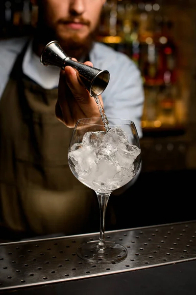 Čiré víno pohár sklo, ve kterém barman jemně nalévá tekutinu z jigger — Stock fotografie