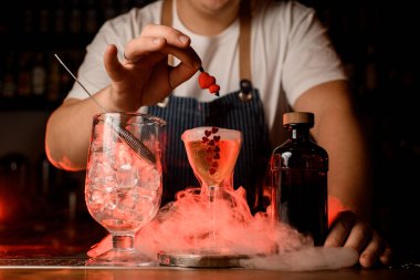 Bardak, şişe ve bir bardak içkiyi barın üstünde dumanla karıştır. Kırmızı arka plan