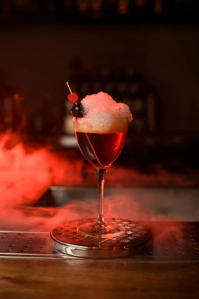 Close-up de copo de vinho com coquetel espumoso decorado com baga vermelha e pequeno coração no bar — Fotografia de Stock