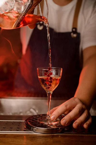 Küçük kırmızı kalplerle süslenmiş güzel bir şarap kadehi manzarası ve içine bir jet dolusu içki.. — Stok fotoğraf