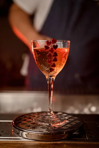 Primo piano di bicchiere da vino con bevanda decorata con piccoli cuori rossi in piedi sul bar — Foto Stock