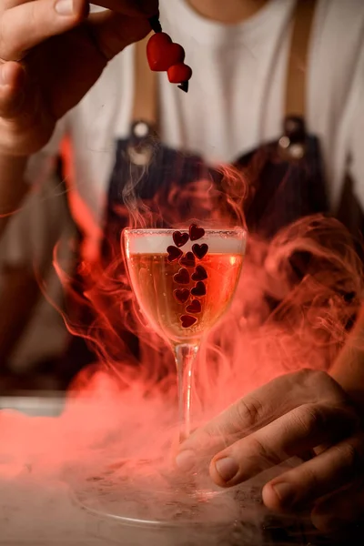 Close-up van mooi glas met drank met decoratieve rode hartjes op de bar en rook eromheen — Stockfoto