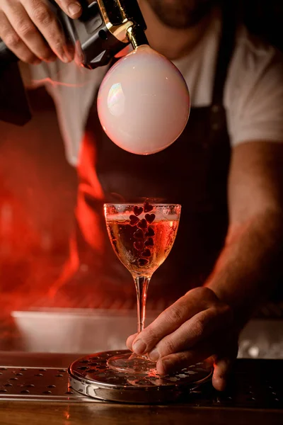 Maschio mano tiene bicchiere da vino con bevanda decorata con cuori e fare bolla d'aria fumosa da Blaster sapore — Foto Stock