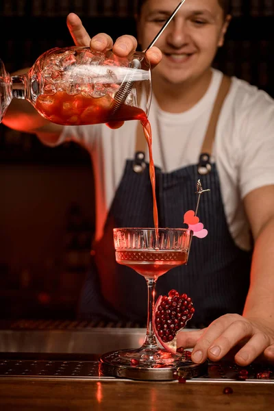 Mano de camarero sostiene taza de mezcla con cóctel y vierte suavemente en la copa de vino — Foto de Stock