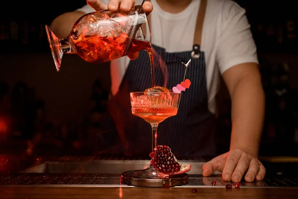 Vista frontal de la copa de vino de cristal en la que se vierte cóctel al vapor de la taza de mezcla — Foto de Stock