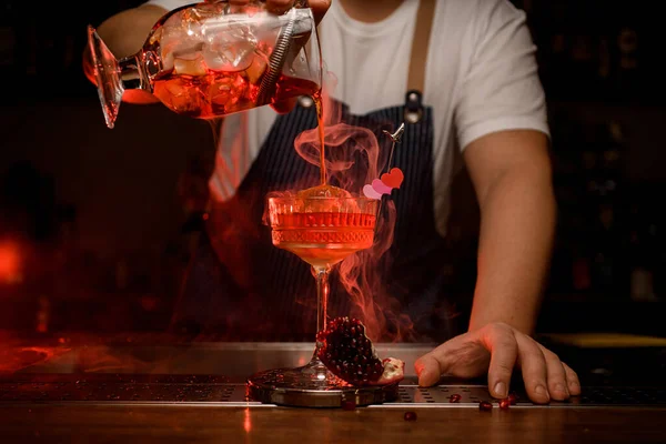 Ottima vista del bicchiere di vino di cristallo in cui viene versato il cocktail fumante dalla tazza di miscelazione — Foto Stock