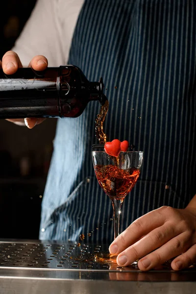 Közelkép egy borospohárról, amit egy szívvel díszítettek, amibe a csapos alkoholt önt az üvegből. — Stock Fotó