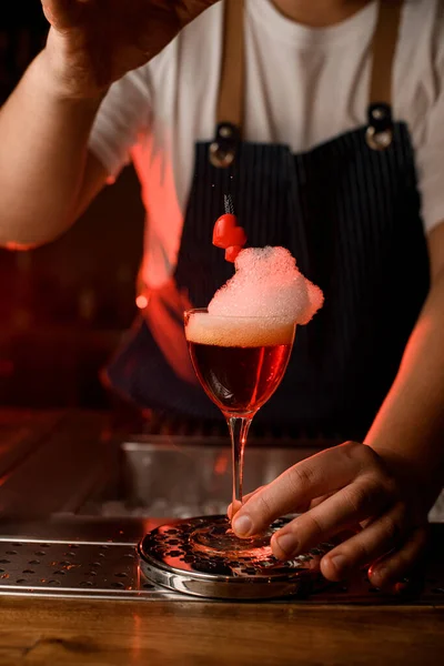 Copo de vinho com bebida decorada com espuma branca e pequeno coração vermelho no bar — Fotografia de Stock