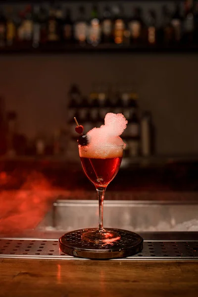 View of glass with foamy cocktail decorated with red berry and small heart on the bar — Stock Photo, Image
