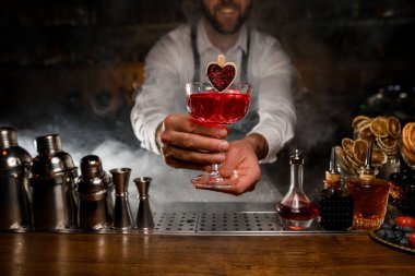 Gülümseyen barmen bir bardak kırmızı alkollü içecek servis ediyor.