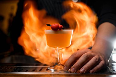 Barmen şeffaf bardakla sarı, lezzetli alkollü içki tutuyor.