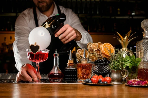 Barista che tiene cocktail alcolici rossi decorati con piccolo cuore — Foto Stock