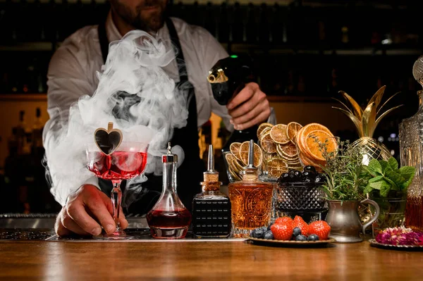 Barman drží červený chutný alkoholický koktejl a dělá kouř — Stock fotografie