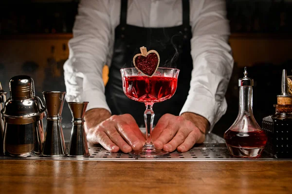 Handen van een mannelijke barman die glas met rode alcoholcocktail vasthoudt — Stockfoto
