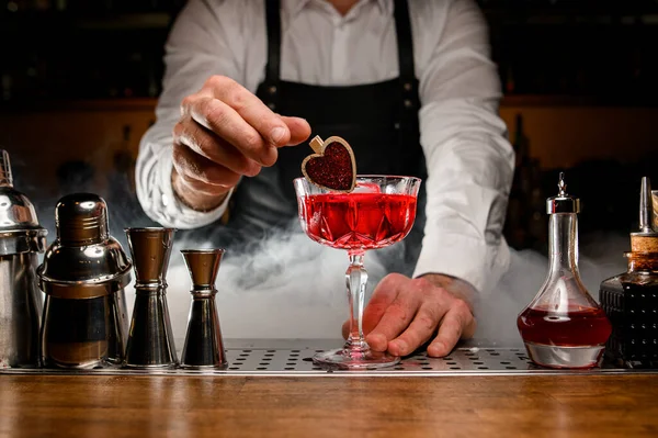 Primer plano de vidrio con cóctel alcohólico que el camarero masculino decora suavemente con un pequeño alfiler de madera — Foto de Stock