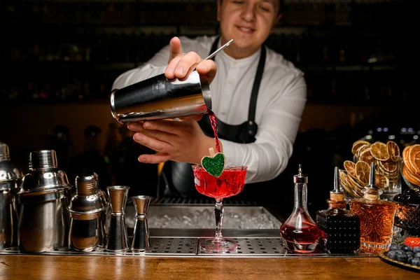 Чоловік бармен поливає червоний свіжий алкогольний напій у склянку — стокове фото