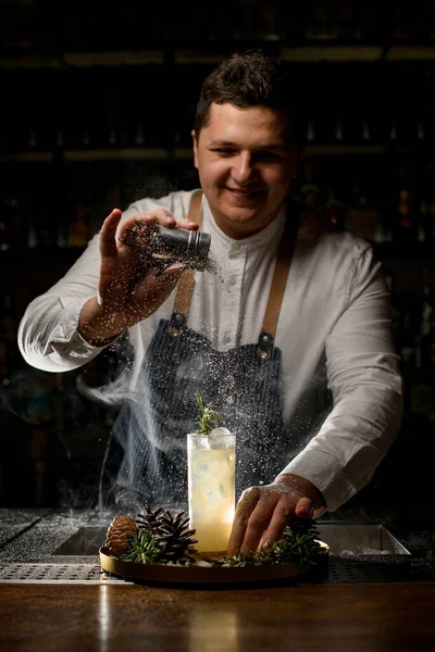 Schöner lächelnder Barmann dekoriert kalten alkoholischen Cocktail vorsichtig mit Zuckerpuder — Stockfoto