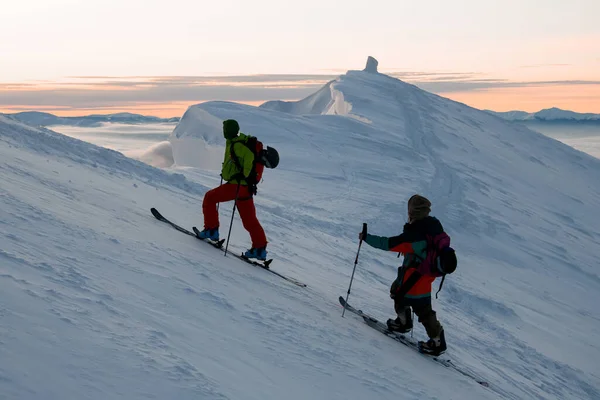 İki erkek kayakçı karlı bir dağın tepesine tırmanıyor. — Stok fotoğraf