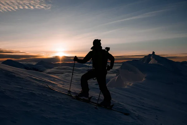 Silhueta de um esquiador contra o pano de fundo do belo céu e nascer do sol — Fotografia de Stock