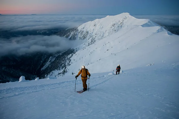 Vue imprenable sur la haute chaîne de montagnes enneigée et les skieurs marchant le long de celle-ci — Photo