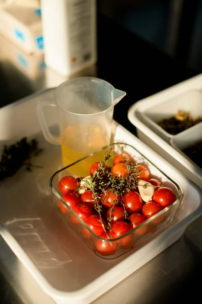 Красивые ярко-красные помидоры и веточки зелени в прозрачной квадратной чаше — стоковое фото