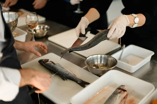 Handen van chef snijdt de vis op een snijplank — Stockfoto