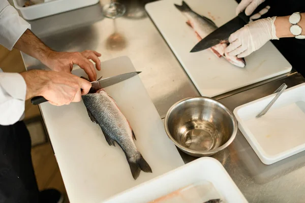 Вид на стол, на котором руками поваров режут рыбу — стоковое фото