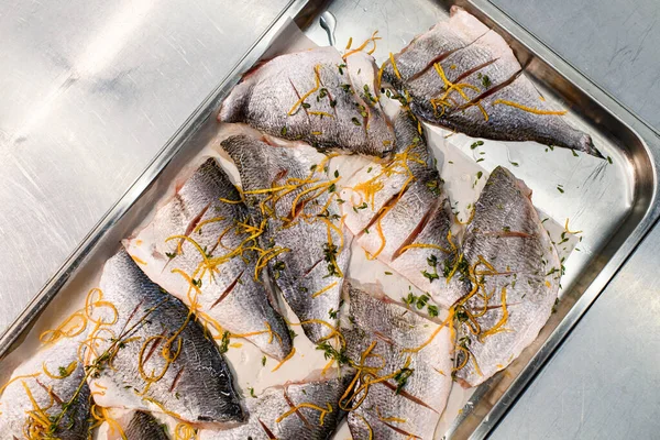 Top view of slices of raw fish with cuts with grated carrots and herbs on baking sheet — Stock Fotó