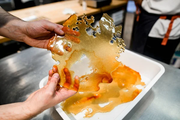 Belle croûte de sucre au caramel congealed doré transparent dans les mains masculines — Photo