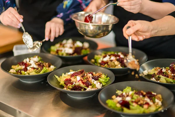 Вид на тарелки с салатом и руками людей, которые добавляют ингредиенты. Концепция шведского стола и питания — стоковое фото