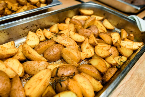 Baharatlı patates dilimleri ve metal tepside biberiye.