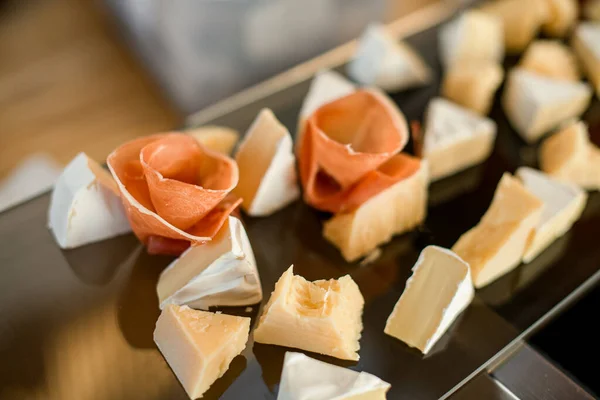 Zbliżenie plasterków sera brie ozdobionego cienkim plasterkiem prosciutto — Zdjęcie stockowe