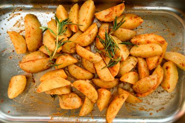 Metal tepside baharatlı ve biberiyeli patates dilimlerinin üst görüntüsü