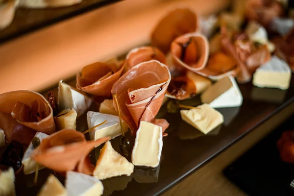 Primer plano de trozos rebanados de delicioso queso brie y finas rebanadas de jamón y salami —  Fotos de Stock
